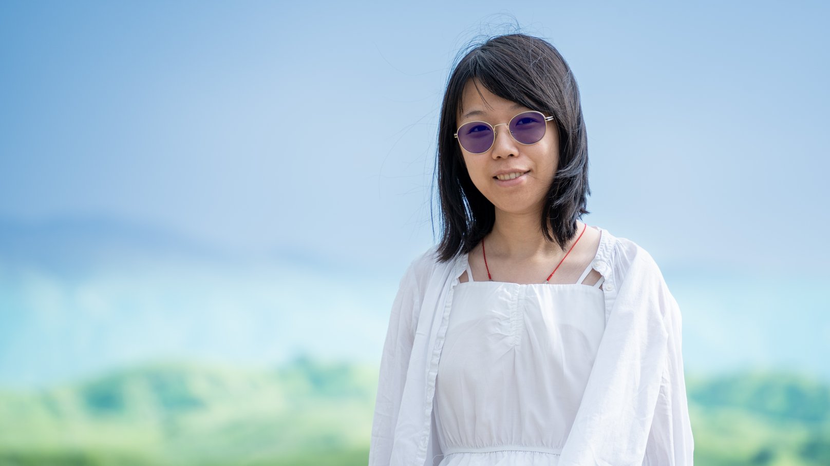 Sishi Wu outdoors, with green hills behind her